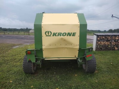 Krone Vario Pack round baler in green and beige with large tires on grassy field.