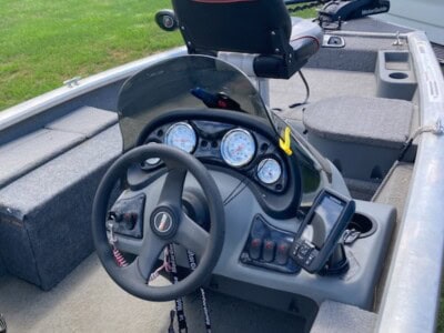 Fishing boat interior with steering wheel, dashboard, and Tracker outboard motor.