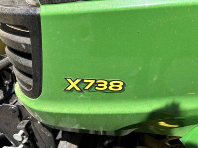John Deere X738 lawn tractor with green body and black grille.
