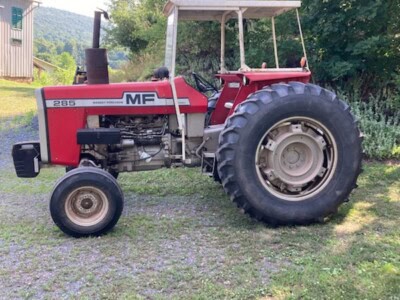 Red Massey Ferguson 215 tractor with canopy, large rear tires, and open engine compartment on grassy field.