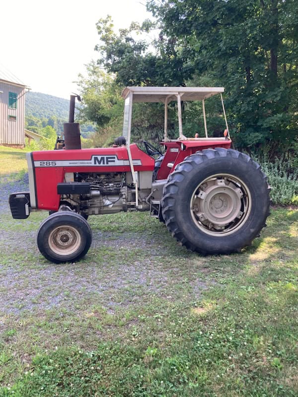 Red Massey Ferguson 215 tractor with canopy, large rear tires, and open engine compartment on grassy field.