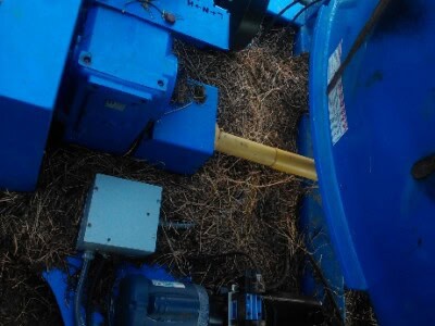 Blue stationary TMR mixer with motor and hydraulic components in outdoor setting.