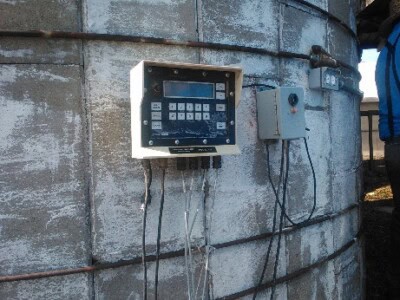 Electronic control panel and sensors on concrete grain silo for monitoring.