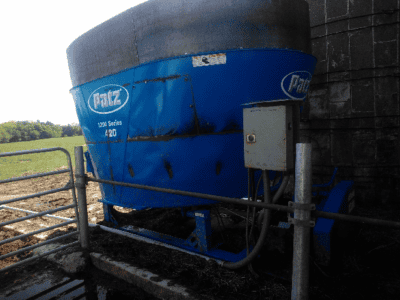Patz 420 stationary TMR mixer with blue body and black top, mounted on a farm.
