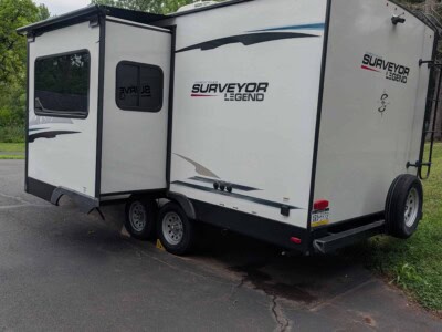 2021 Forest River Surveyor Legend travel trailer with slide-out and black wheels.