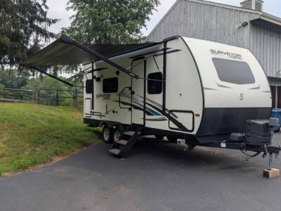 2021 Forest River Surveyor 203RLKE travel trailer with awning extended on paved driveway.