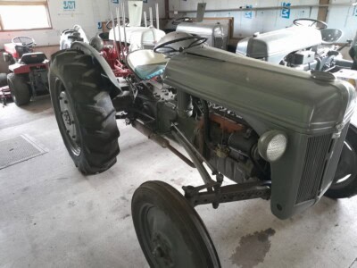 1939 Ford 9N vintage tractor with large rear tires and metal hood in indoor storage.