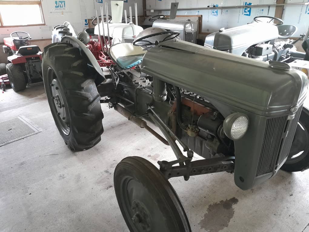 1939 Ford 9N vintage tractor with large rear tires and metal hood in indoor storage.