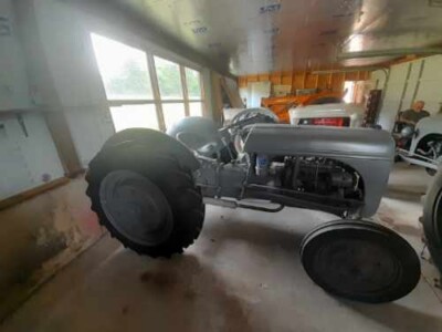 Restored 1939 Ford 9N tractor with open engine and large rear tires in a workshop.