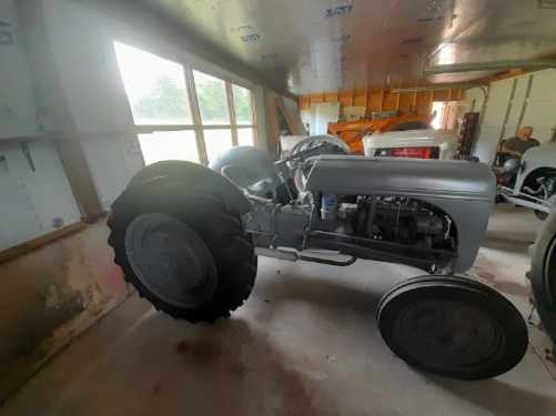 Restored 1939 Ford 9N tractor with open engine and large rear tires in a workshop.