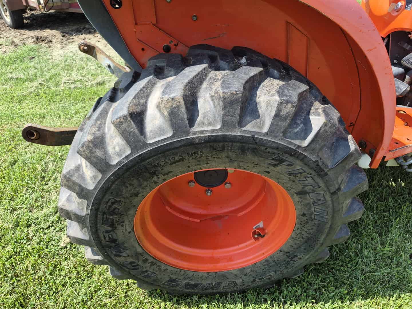 Resized_20260720_152929 Large Kubota tractor tire with deep treads and orange rim, part of the L3800D model.
