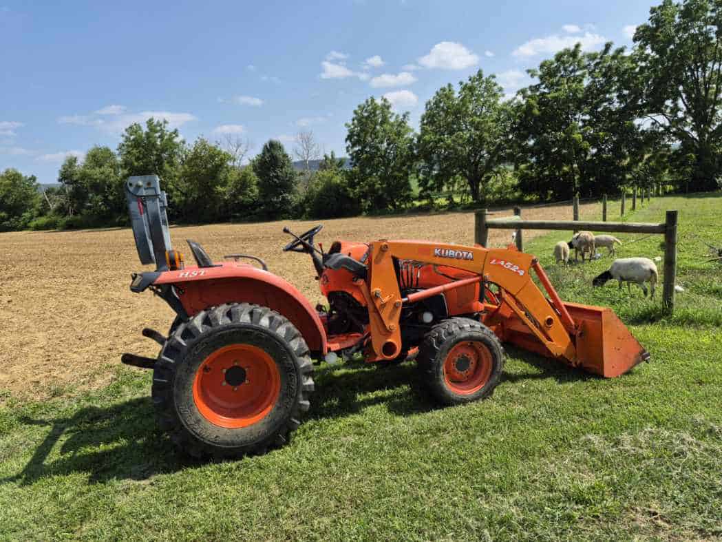 KUBOTA L3800D Compact Tractor with Loader Orange Kubota L3800D compact tractor with front loader and rear ballast weight on a farm.
