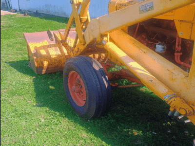 Yellow construction equipment with a large blade and black tires on green grass.