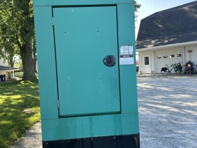 CUMMINS ONAN 50 kW generator in teal color with black base, outdoor setting.