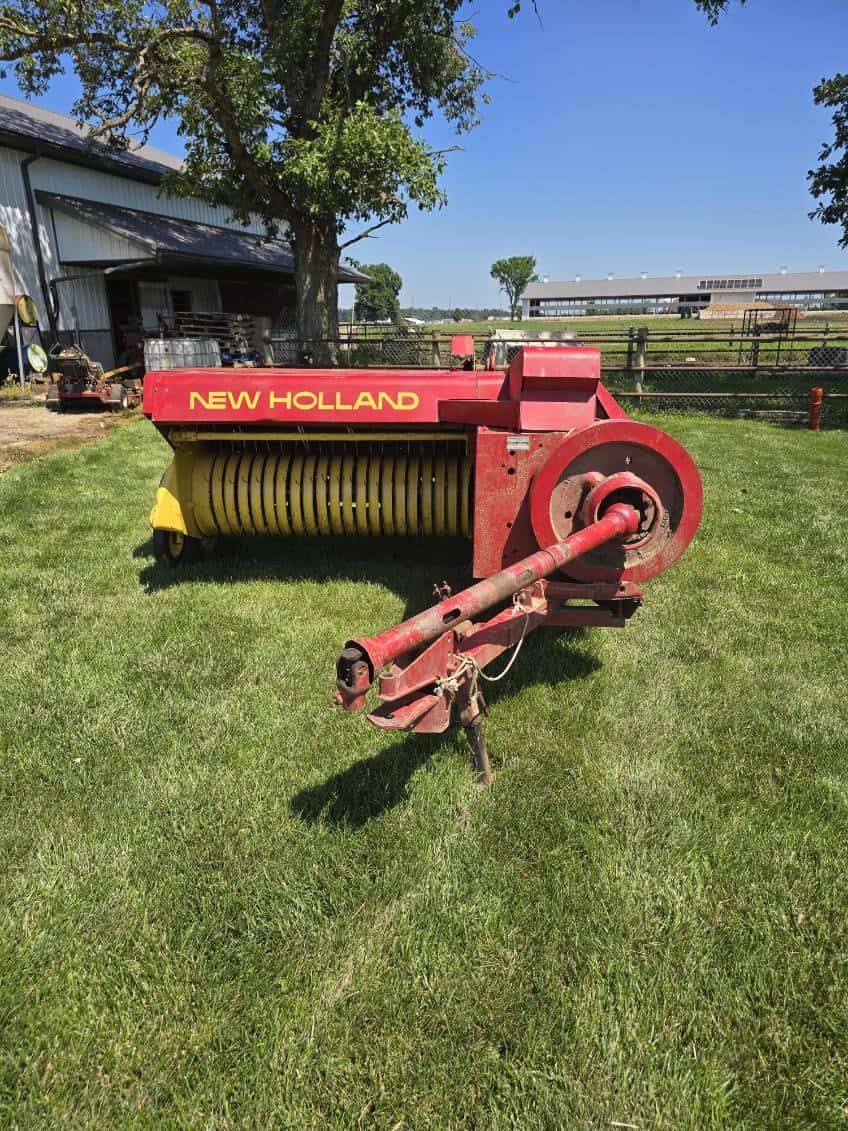 image000000 (52) New Holland 273 hay rake with red and yellow color, large wheels, and tines for hay collection.