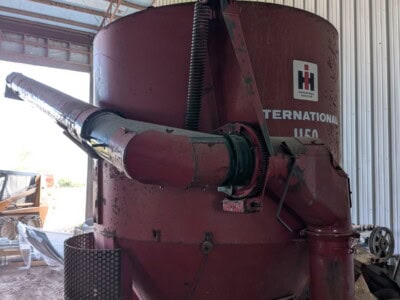 International 1150 grain auger with red finish and large hopper, stored indoors.