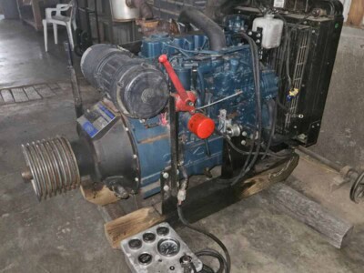 Blue diesel power unit with radiator and control panel in workshop setting.