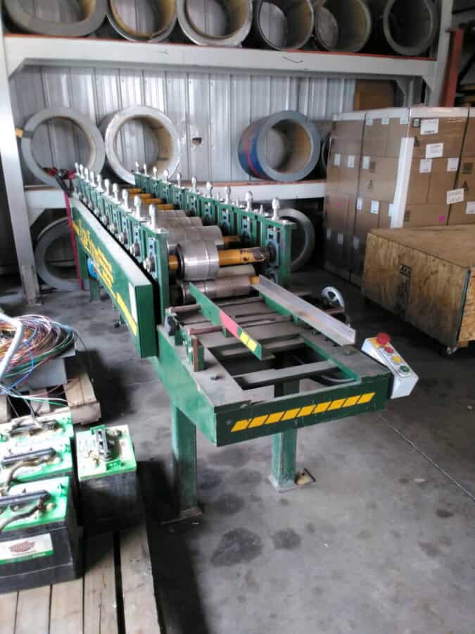Industrial beaded fascia machine with rollers and control panel in warehouse setting.
