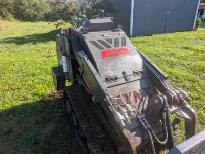 2023 Lynx LX-1200 compact track loader with cab and hydraulic attachments on grassy area.