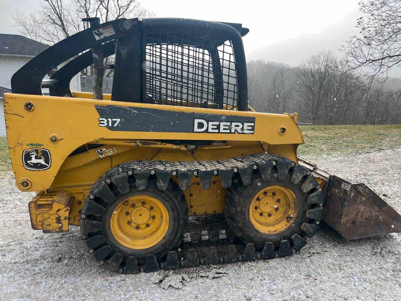 image000003 (18) John Deere 317 compact track loader with bucket attachment, yellow and black, in outdoor setting.