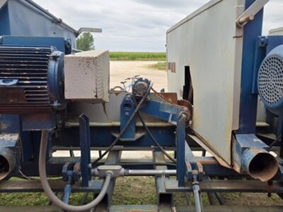 Industrial equipment with blue and white components on a railway track under cloudy sky.