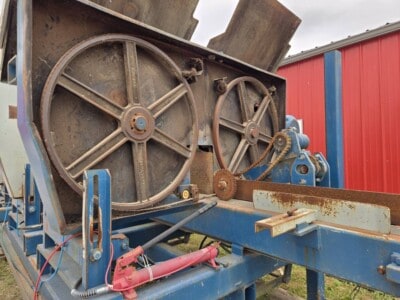 Industrial equipment with large wheels and rusted components, blue frame, and red hydraulic parts.