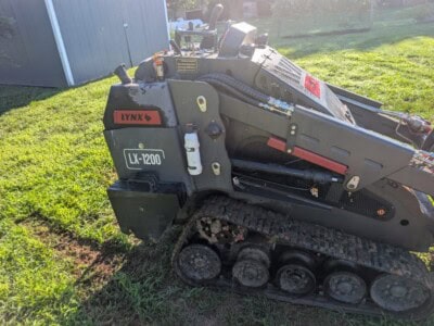 2023 Lynx LX-1200 compact tracked loader with cab and rubber tracks on grassy area.