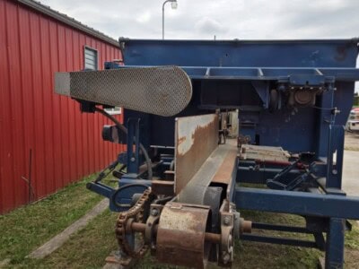 Blue agricultural trailer with rusted components and hydraulic system.
