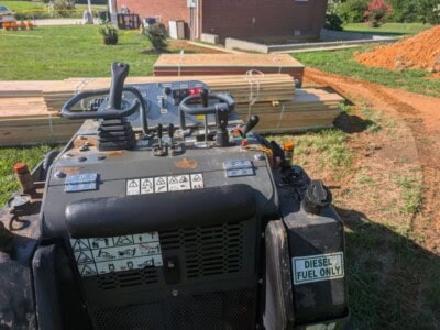 Construction equipment control panel with levers and warning labels at a building site.