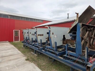 Large industrial conveyor system with multiple sections and rollers outside red warehouse.