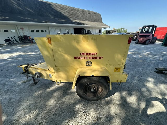 Yellow emergency disaster recovery trailer with single axle and black wheel, parked on gravel.
