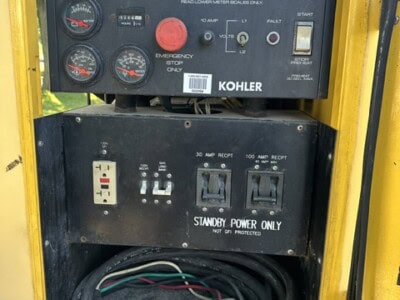 Kohler generator control panel with gauges and switches in yellow enclosure.