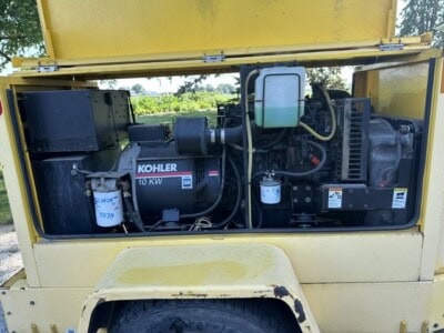 Kohler 10KW generator inside yellow enclosure with control panel and engine components.