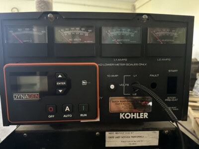 Kohler generator control panel with gauges and digital display, black and orange design.