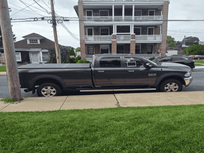 Black 2014 RAM 2500 Big Horn pickup truck parked on street in front of a multi-story building.