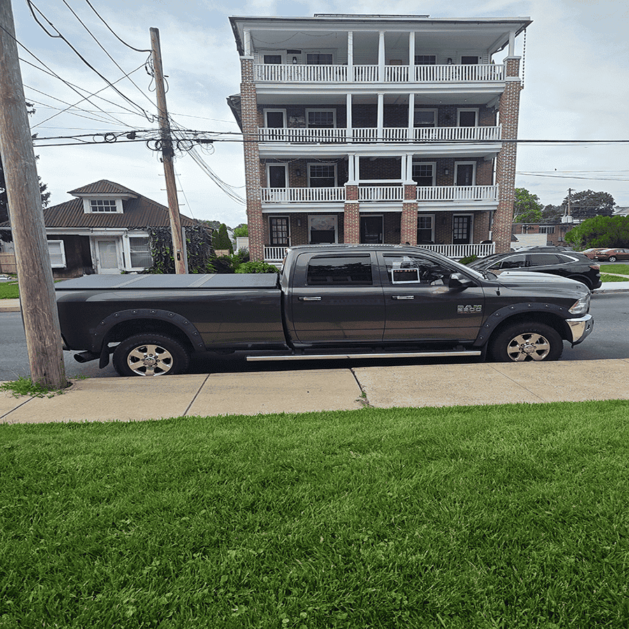 Black 2014 RAM 2500 Big Horn pickup truck parked on street in front of a multi-story building.