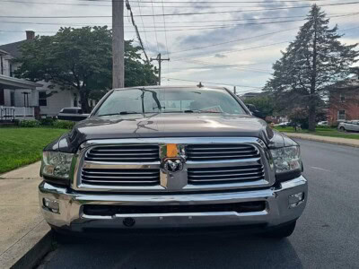 2014 RAM 2500 Big Horn pickup truck parked on street with trees and houses in background.