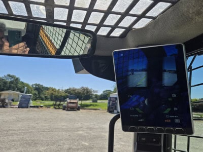 Rearview camera monitor inside construction equipment with outdoor view.