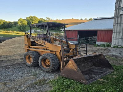 CASE 1835 skid steer loader with bucket attachment on farm ground.