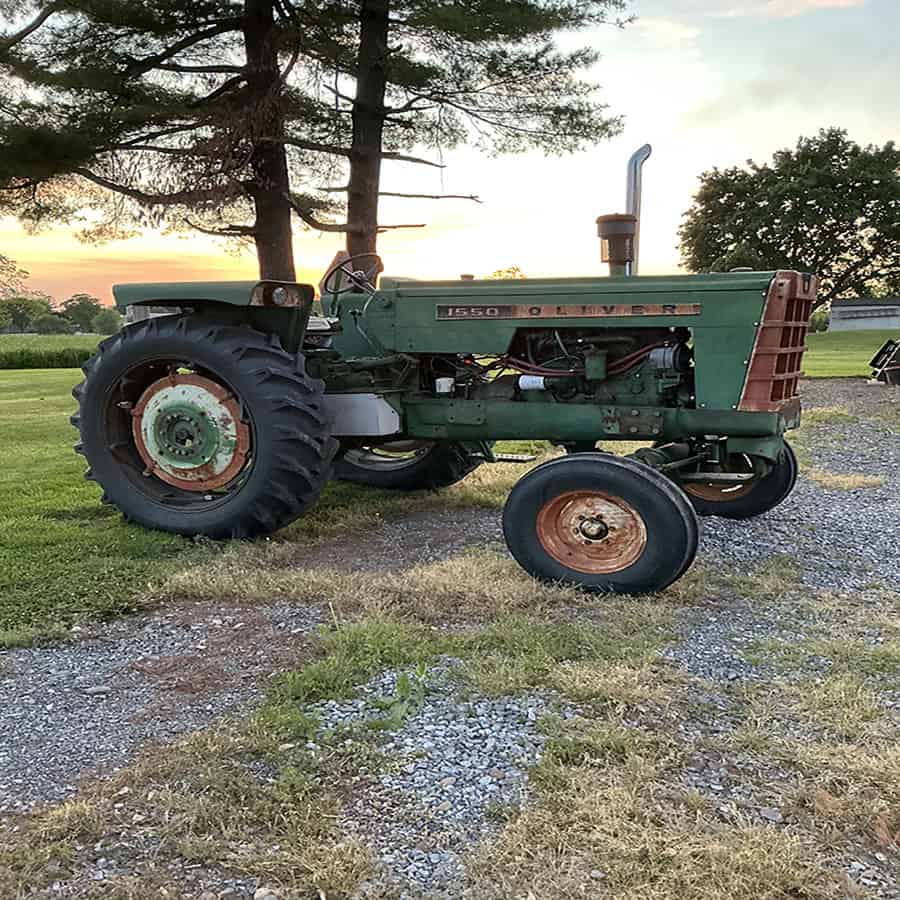 Oliver 1550 Tractor in Field at Sunset Oliver 1550 vintage tractor with green body and rusted wheels in a rural field at sunset.