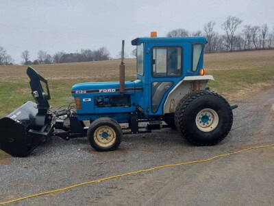 Ford 2120 tractor with front loader attachment on a gravel surface.