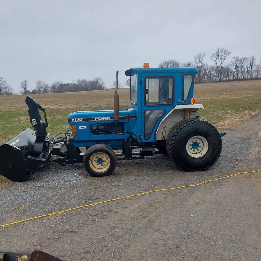 Ford 2120 tractor with front loader attachment on a gravel surface.