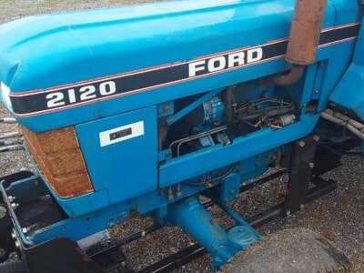 Ford 2120 tractor with blue body and visible engine components.