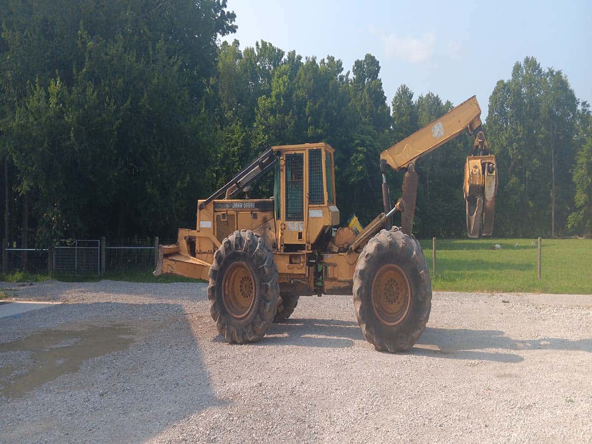 John Deere 748 wheel loader with front bucket and rear hydraulic arm, yellow color, parked on gravel surface.