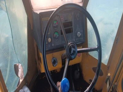Interior view of a John Deere 748 tractor with steering wheel and dashboard controls.