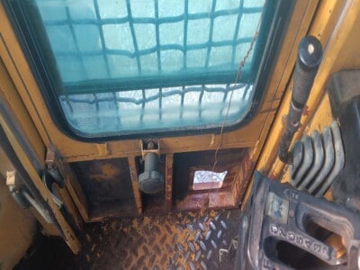 Cab interior of a yellow John Deere 748 with visible controls and window view.