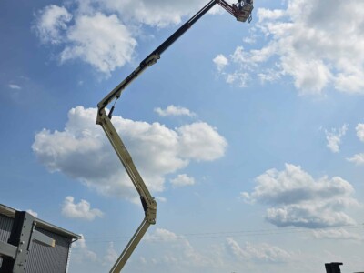 2015 JLG X700AJ boom lift with extended arm and basket against cloudy sky.