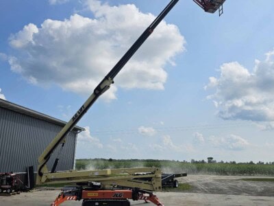 2015 JLG X700AJ boom lift with extended arm and basket, outdoor setting under blue sky with clouds.
