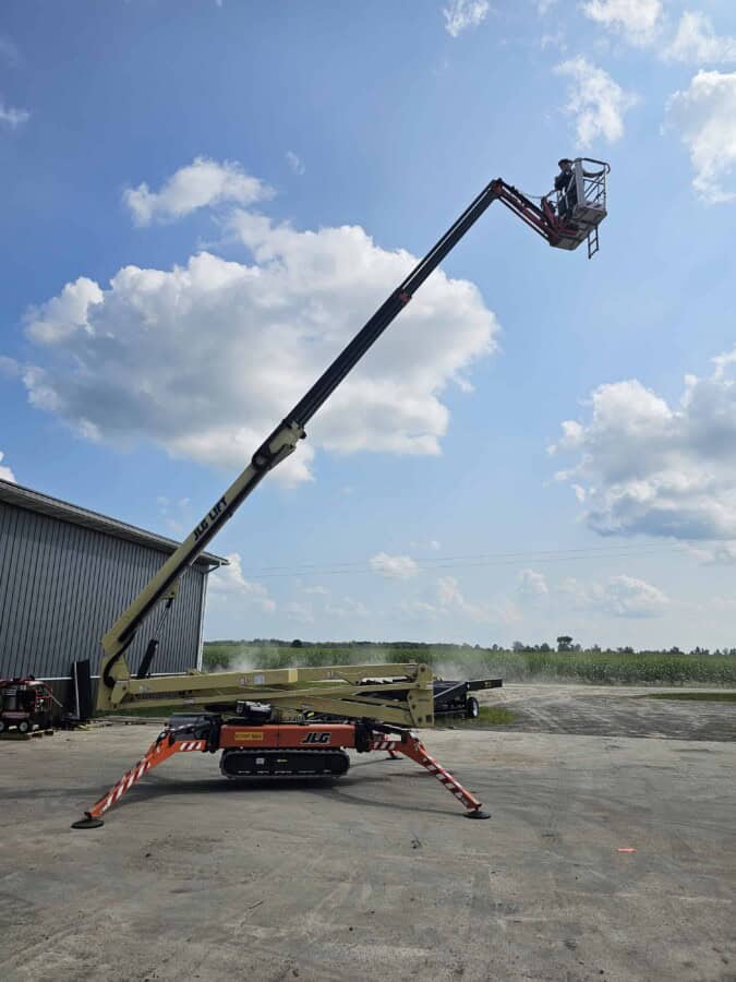 2015 JLG X700AJ boom lift with extended arm and basket, outdoor setting under blue sky with clouds.