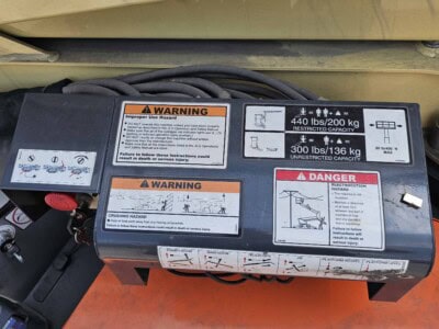 Safety warning labels on hydraulic lift equipment with weight limits and hazard symbols.